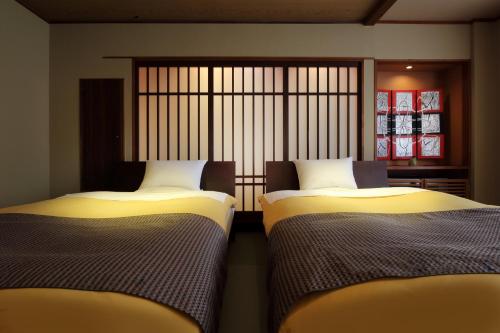two beds sitting next to each other in a room at Yamayuri no Yado in Hanamaki