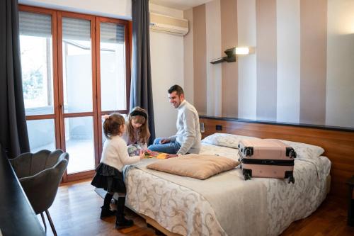 a man and two children sitting on a bed at EcoHotel Ristorante Milano in Borgo a Mozzano