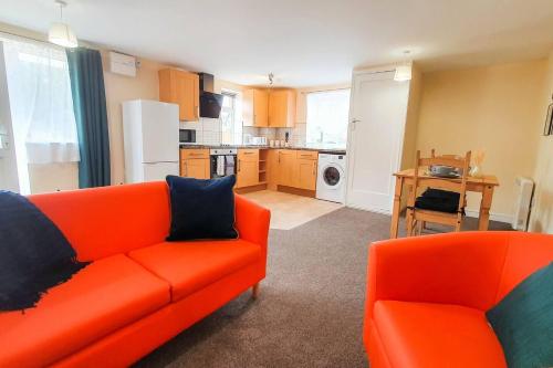 a living room with an orange couch and a kitchen at Charming 1-Bed Apartment in Stroud in Stroud
