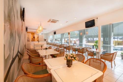 un comedor con mesas, sillas y ventanas en Victoria Inn, Penang, en George Town