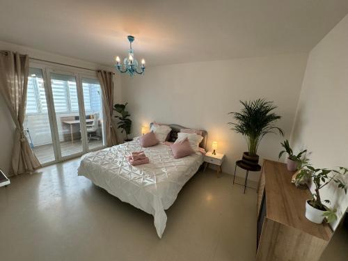 Schlafzimmer mit einem Bett mit rosa Kissen und einem Kronleuchter in der Unterkunft Villa du Parc de Vaugrenier in Villeneuve-Loubet