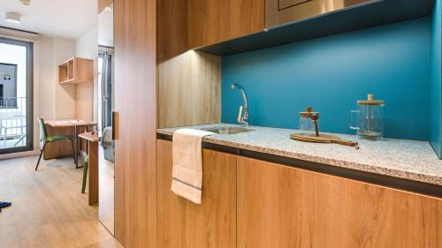 - une cuisine avec un évier et un mur bleu dans l'établissement Livensa Living Studios - Valencia Viveros, à Valence
