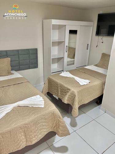 a bedroom with two beds and a mirror at Hotel Aconchego Cearense in Fortaleza