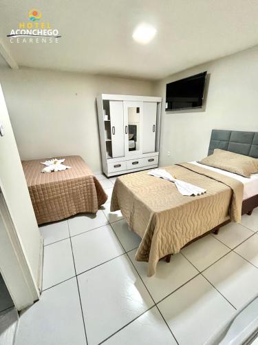 a room with two beds and a tv in it at Hotel Aconchego Cearense in Fortaleza