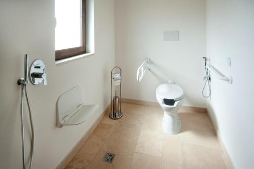 a white bathroom with a toilet and a window at Masseria Dirupo in Noci