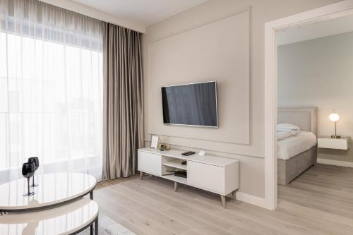a white room with a bed and a table and a tv at RentPlanet - Apartament Ślężna in Wrocław