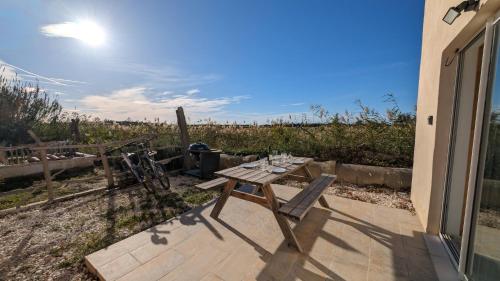 a picnic table with wine glasses on a patio at Appartement au coeur des rizières in Salin-de-Giraud