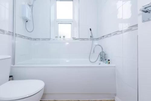 a white bathroom with a toilet and a bath tub at Spacious 4-Bed House Manchester in Manchester