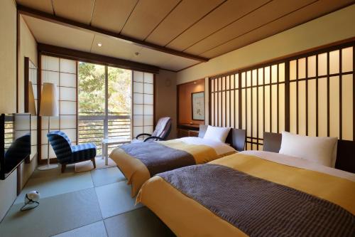 a hotel room with two beds and a window at Yamayuri no Yado in Hanamaki