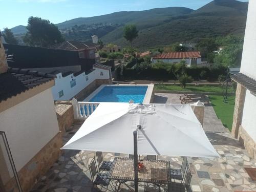 a white umbrella and chairs and a swimming pool at Buen Estar, piscina, barbacoa, jacuzzi en Valencia in Turís