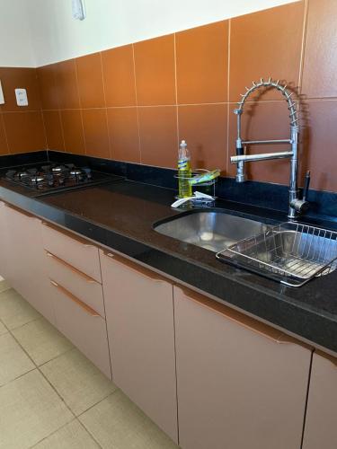 a kitchen counter with a sink and a stove at Casa 90m, dois quartos, próxima às praias in Maceió
