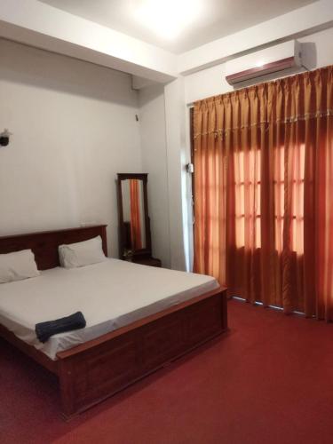 a bedroom with a large bed and a window at New Dulmi Guest House. in Denipitiya