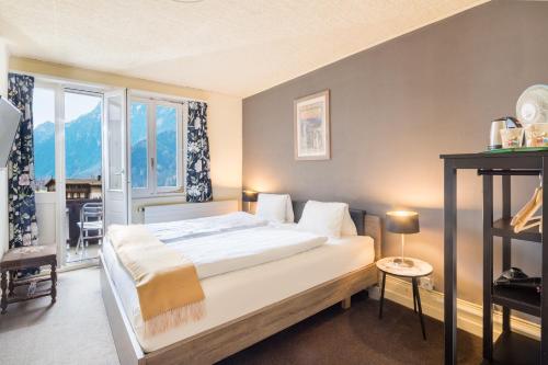 Un dormitorio con una cama grande y una ventana en Alpenrose Hotel and Gardens en Wilderswil