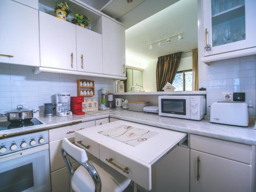 a kitchen with white cabinets and a white counter top at Yianni's Home-Comfort Apartment in Volos in Volos