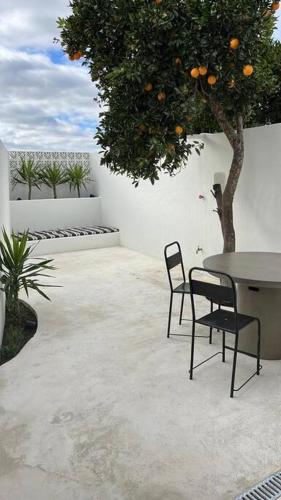 a patio with a table and chairs and an orange tree at Casa Olarias in Grândola