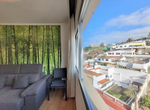 een woonkamer met een bank en een groot raam bij Apartamento Mencey Bencomo in Puerto de la Cruz