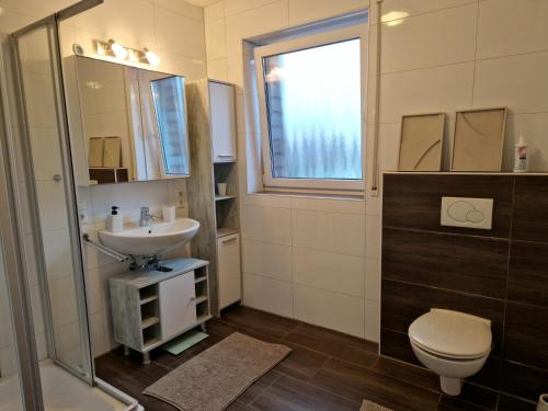 a bathroom with a sink and a toilet and a window at Cozy Apartment: Design Superior Suite Zentral - Küche - Balkon in Cloppenburg