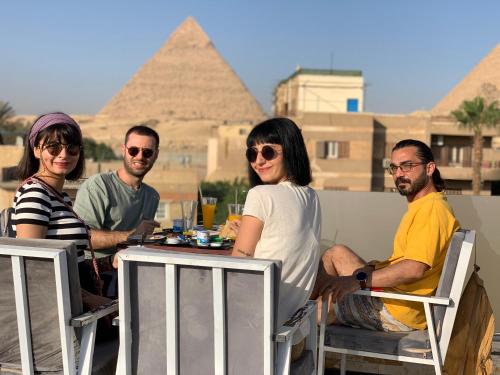 a group of people sitting at a table in front of pyramids at Locanda pyramids view in Cairo