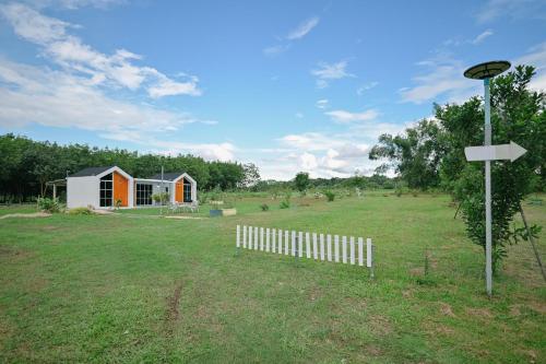 a house in a field with a fence at ไร่นภาดลรีสอร์ท in Mae Suai