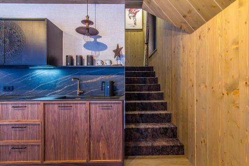 a staircase leading up to a kitchen with wooden cabinets at Rozmus Apartamenty in Bukowina Tatrzańska