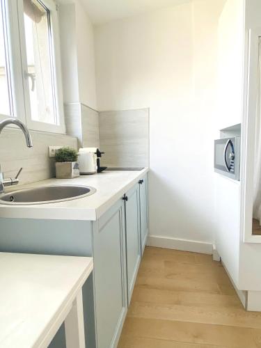 une salle de bain blanche avec un lavabo et une fenêtre dans l'établissement Architect studio near Montmartre, à Paris