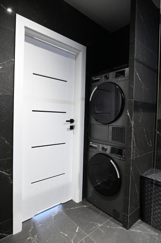 uma porta branca ao lado de uma máquina de lavar roupa e um micro-ondas em APARTAMENT TOPaZ 30 em Konin