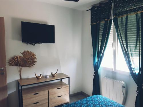 a bedroom with a dresser and a tv on the wall at Chambres Privées " Les Pins " in Béziers