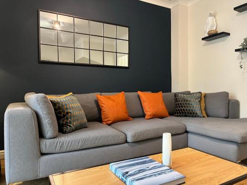 sala de estar con sofá gris y almohadas de color naranja en Stamford House - Short Stays and Contractors, en Lincolnshire