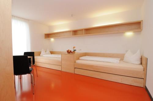 Olympiazentrum Vorarlberg في دورنبيرن: غرفة نوم مع سرير مع أرضية برتقالية