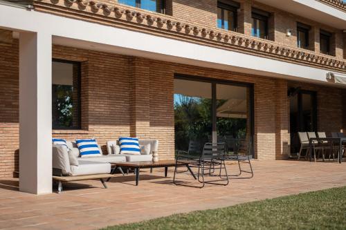eine Terrasse mit Sofas, einem Tisch und Stühlen in der Unterkunft Gava Beach Villa by Olala Homes in Gavà