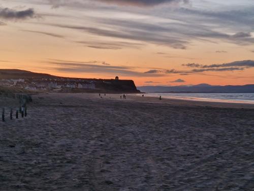 a group of people walking on the beach at sunset at Hunters Glebe Country Apartment in Castlerock