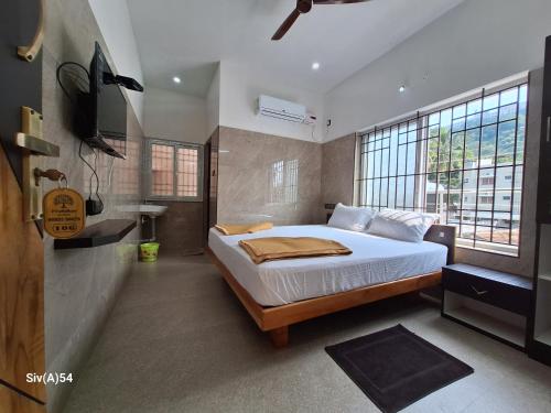 a bedroom with a bed and a large window at Viruksham Residency in Palani