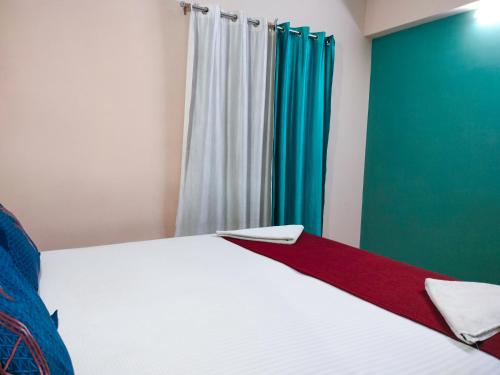 1 dormitorio con 1 cama con cortinas blancas y verdes en Primera Extended Stay Apartments, en Bangalore