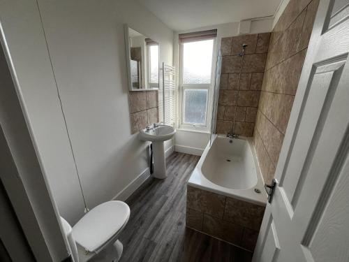 a bathroom with a toilet and a tub and a sink at Magnificent 6-Bedroom Queen House in Beeston Awaits You! in Nottingham