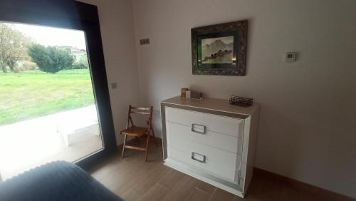 a bedroom with a dresser and a large window at La finca del Goño in Pravia
