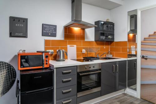 a kitchen with black appliances and an orange tile wall at ALTIDO Trendy City Centre Studio in Birmingham