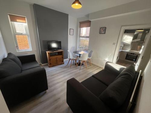 a living room with a couch and a tv and a table at Magnificent 6-Bedroom Queen House in Beeston Awaits You! in Nottingham