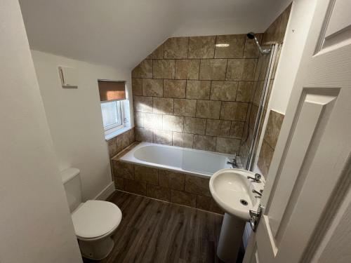 a bathroom with a tub and a toilet and a sink at Magnificent 6-Bedroom Queen House in Beeston Awaits You! in Nottingham