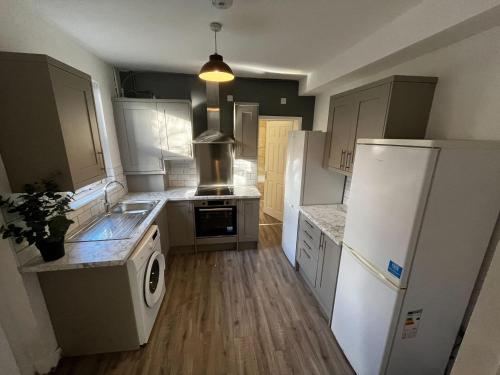 a kitchen with a refrigerator and a sink and a stove at Magnificent 6-Bedroom Queen House in Beeston Awaits You! in Nottingham