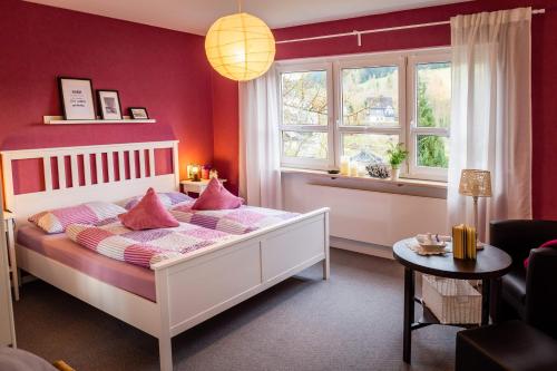 una camera da letto con un letto bianco e cuscini rosa di Ferienwohnung Haus am Sommerberg a Ludwigsstadt