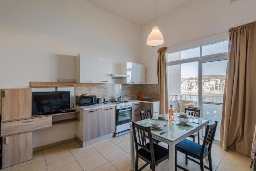eine Küche mit einem Tisch und einem Esszimmer in der Unterkunft Blue Harbour 2 bedroom Seafront Apartments with stunning seaviews - by Getawaysmalta in St Paul's Bay