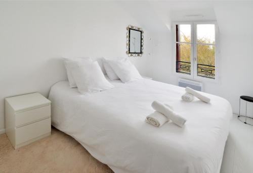 une chambre avec un lit blanc avec deux serviettes dessus dans l'établissement L'Amandier Disneyland Paris 4 personnes et 1 bébé, à Bailly-Romainvilliers