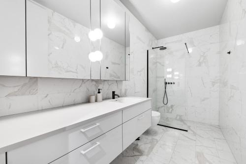 a white bathroom with a sink and a toilet at Harbour Lux 3BR & 2BA in the Heart of the City with Free Parking in Reykjavík