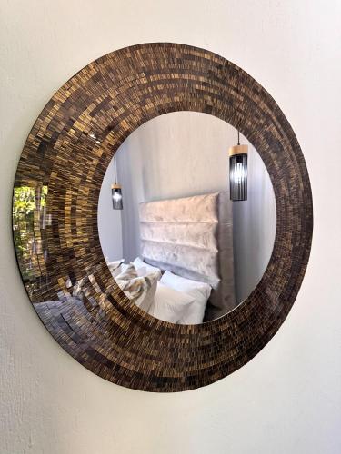 a wicker mirror hanging on a wall with a bed at Gardens Villa in Nelspruit
