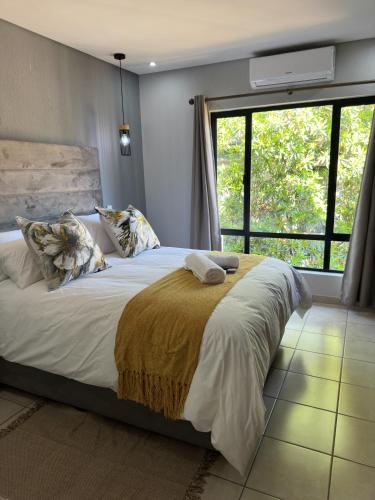 a bedroom with a large bed with a large window at Gardens Villa in Nelspruit