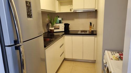 una pequeña cocina con armarios blancos y nevera. en Lushfield Boracay Guest House en Boracay