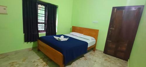 a bedroom with a bed with a blue blanket and a window at Empire HomeStay in Kalpetta