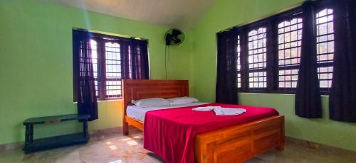 a bedroom with a bed with a red blanket on it at Empire HomeStay in Kalpetta