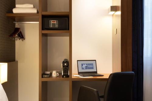 Holiday Inn Express Amiens, an IHG Hotel في أميان: غرفة بها مكتب مع جهاز كمبيوتر محمول