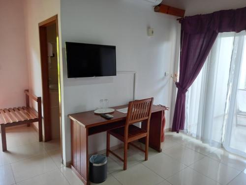 a room with a desk and a television on a wall at Hôtel Saïfee International in Toliara